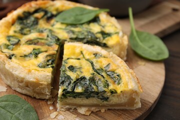 Delicious pie with spinach on wooden table, closeup