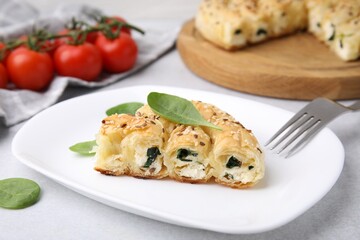 Piece of delicious puff pastry with spinach on light table, closeup