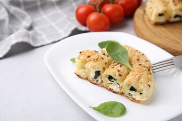 Piece of delicious puff pastry with spinach on light table
