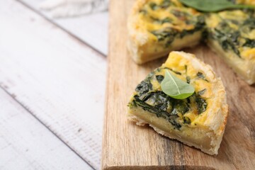 Piece of delicious pie with spinach on white wooden table, closeup. Space for text
