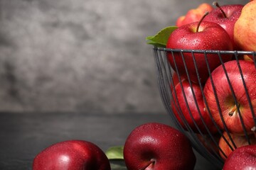 Fresh ripe red apples with water drops in metal bowl on table, closeup. Space for text