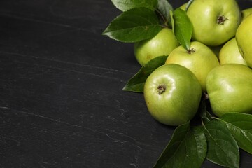 Ripe green apples with leaves on dark grey table, closeup