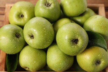 Fresh ripe green apples with water drops in crate, closeup