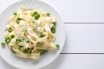 Delicious pasta with green peas on white wooden table, top view. Space for text