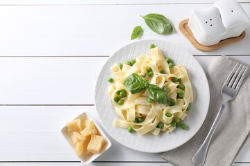 Delicious pasta with green peas served on white wooden table, flat lay. Space for text