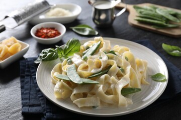 Delicious pasta with green peas and creamy sauce on black table