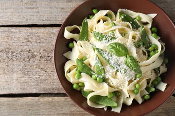 Delicious pasta with green peas and cheese on wooden table, top view. Space for text