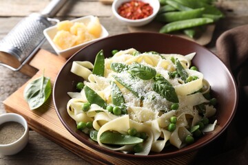 Delicious pasta with green peas and ingredients on wooden table