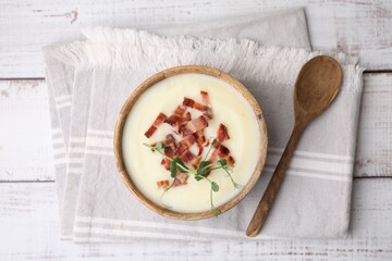 Delicious potato soup with bacon and microgreens in bowl served on wooden table, flat lay