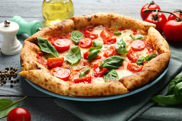 Delicious Margherita pizza and ingredients on gray wooden table, closeup