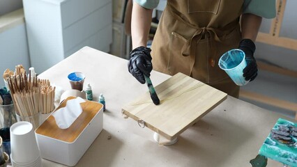 Woman designer create trendy artwork canvas handmade in style liquid art in bright home workshop. Using new contemporary polymer, acrylic and natural materials in professional creative work.