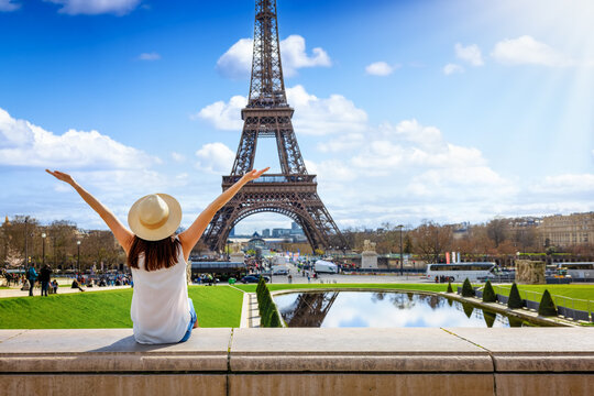 A tourist woman enjoys the beautiful view of the Eiffel Tower in Paris, France, during a sunny spring day