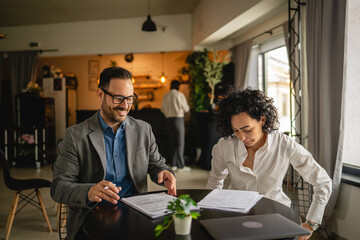 Man and woman colleagues hold documents and work together at cafe