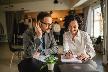 Man and woman colleagues hold documents and work together at cafe