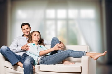 Joyful young couple sitting on a sofa at home
