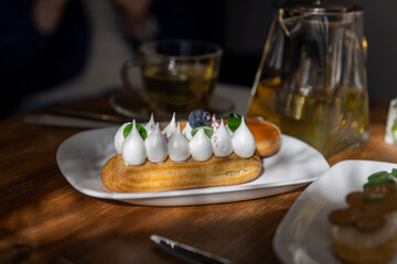 A delightful assortment of pastries on a wooden table bathed in warm sunlight, accompanied by a teapot and teacup, creating a serene cafe ambiance perfect for a leisurely breakfast or brunch