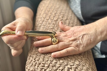 An unknown elderly woman sitting in an armchair makes herself a hand massage with her hand with a...