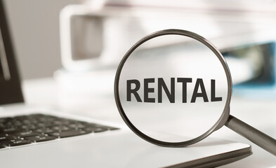 Magnifying Glass Focused on the Word Rental Against a Blurred Background