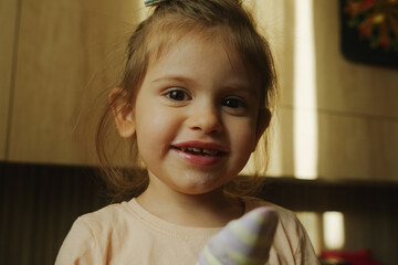 A little girl is smiling and holding a sock in her hand at an event