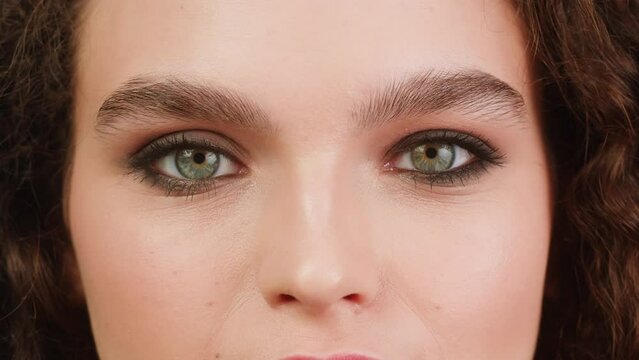 Young attractive brunette woman with curly hair looking and smiling at the camera close-up, Female with smoky eyes make-up. Makeup tutorial.