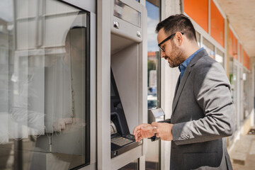 Adult caucasian man stand and hold credit card use cash machine