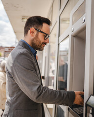 Adult caucasian man stand and hold credit card use cash machine