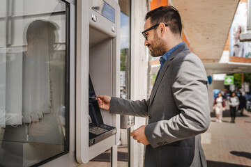 Adult caucasian man stand and hold credit card use cash machine