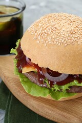 Board with delicious cheeseburger on table, closeup