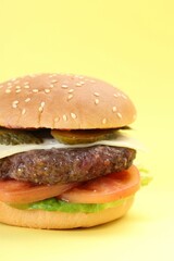 Burger with delicious patty on yellow background, closeup