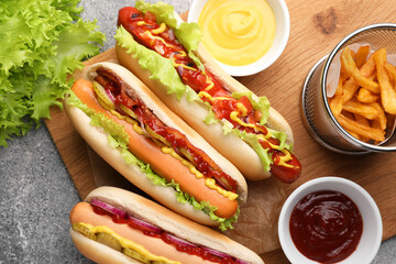 Delicious hot dogs with different toppings served on grey table, flat lay