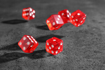 Many red game dices falling on grey textured table