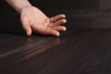 Woman holding hand above black wooden table, selective focus. Space for text