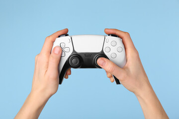 Woman using game controller on light blue background, closeup