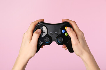 Woman using game controller on pink background, closeup © New Africa