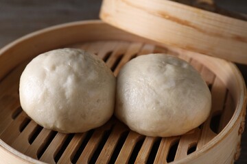 Delicious Chinese steamed buns in bamboo steamer on table, closeup