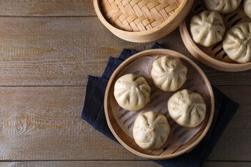 Fototapeta premium Delicious bao buns (baozi) on wooden table, flat lay. Space for text