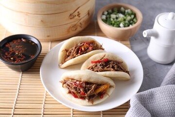 Delicious gua bao (pork belly buns), green onion and sauce on grey textured table, closeup
