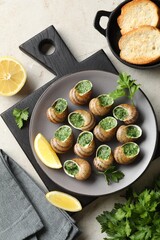 Delicious cooked snails served on light table, flat lay