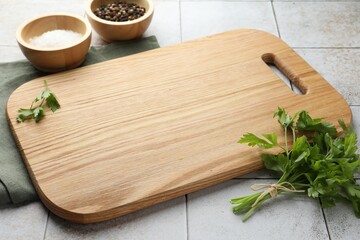 Cutting board, salt, pepper and parsley on white tiled table. Space for text