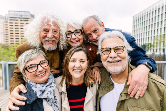 Portrait of happy diverse senior friends standing together at city. Elderly adult people smiling at camera enjoying free time on vacation.