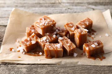 Yummy candies with caramel sauce and sea salt on wooden table