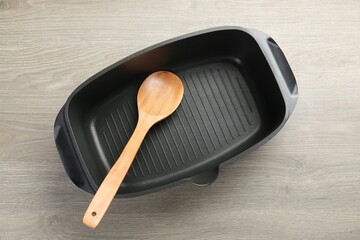 Black pot and spoon on wooden table, top view