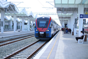 Modern commuter train arriving at a busy urban station on a sunny day