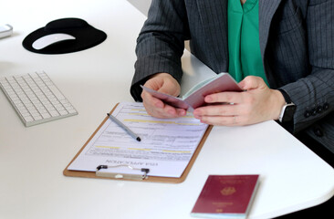 Top view of a woman filling out visa application documents with a German passport on a office table