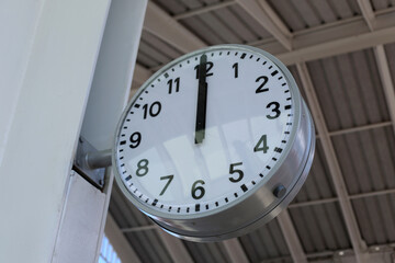 Wall clock showing noon inside industrial building with high ceiling