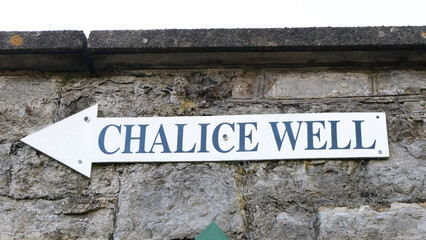 A directional sign post on old brick wall for the popular tourism attraction of Chalice Well...