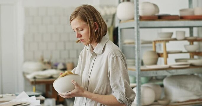 Female Potter Examining Finished Ceramic Bowl in Studio