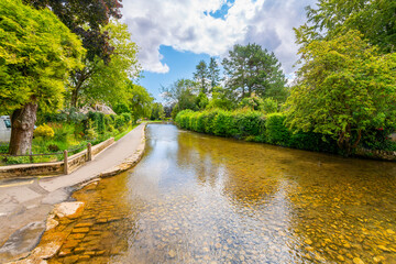 View of the River Windrush as it runs through the picturesque village of Bourton-on-the-Water, England, in the rural Cotswold District of South Central England.
