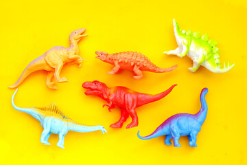 Plastic dinosaur toys on yellow background