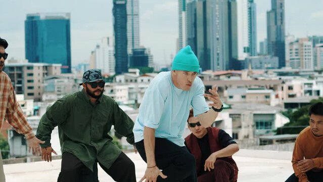 Professional hispanic break dancer practice B boy dance while multicultural friends at roof top. Young modern dancing group doing hip hop movement. Style,fashion,action. Outdoor sport 2024. hiphop.